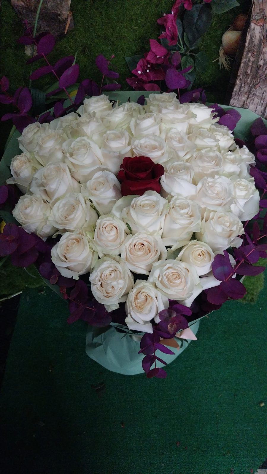 Composición en forma de corazón con rosas blancas y una roja